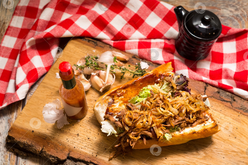 Скачать Сэндвич с остатками ростбифа в Новом Орлеане. Начинка для тушеного ростбифа, приготовленного на медленном огне, с жареными луковыми чипсами и острым соусом. фотосток Ozero
