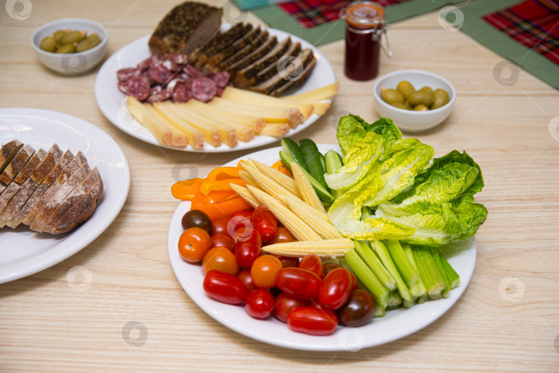 Скачать Тарелка с холодными закусками, такими как свежие помидоры чернослив, мини-кукуруза, стебли сельдерея, листья салата фотосток Ozero