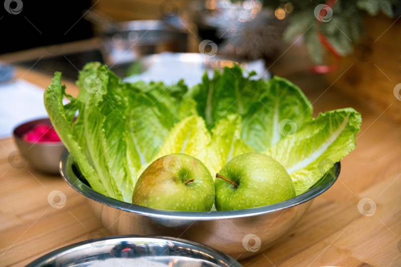 Скачать тарелка со свежими зелеными яблоками и листьями салата. сырые продукты перед приготовлением. фотосток Ozero
