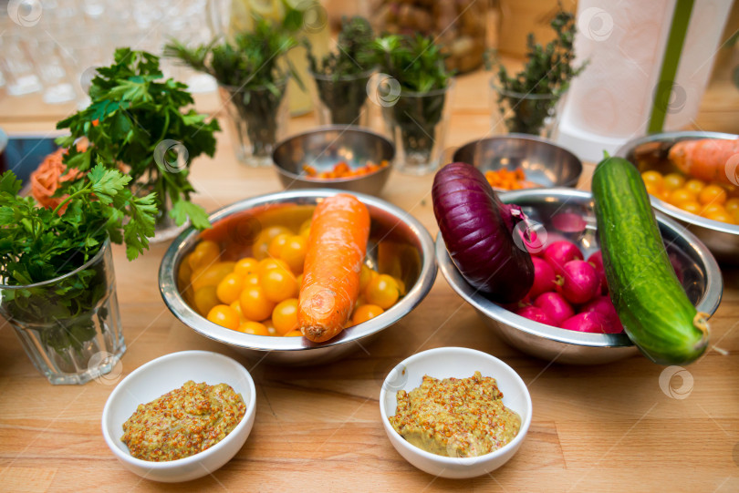 Скачать Овощи и зелень на деревянном столе на кухне. Разноцветные овощи в металлических мисках. фотосток Ozero