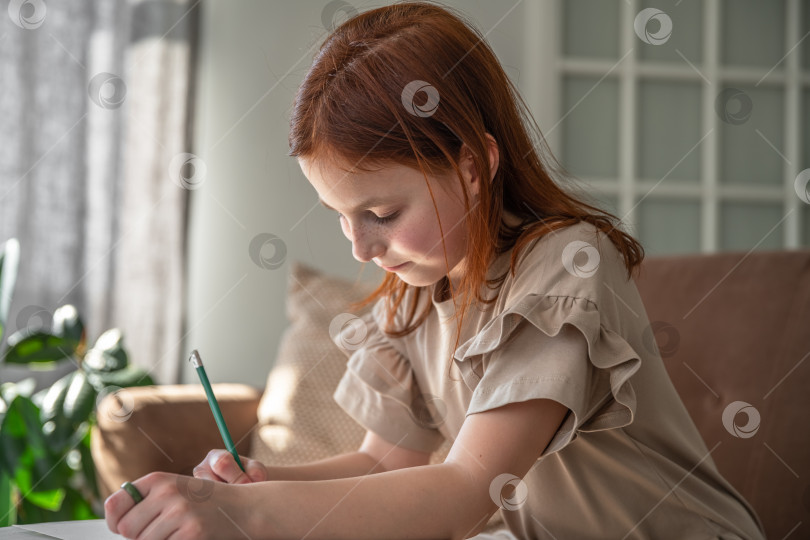 Скачать милая маленькая девочка-подросток рисует ручкой, сидя дома за письменным столом, красивая девочка женского пола, маленький ребенок делает школьную домашнюю работу фотосток Ozero