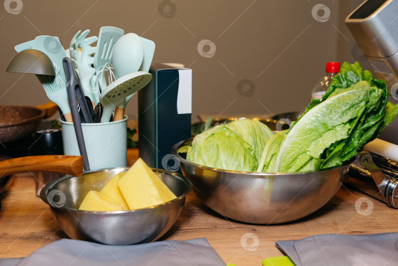 Скачать салат из капусты в металлической миске на деревянном столе на кухне. Большие куски сливочного масла положите в стальную миску. фотосток Ozero