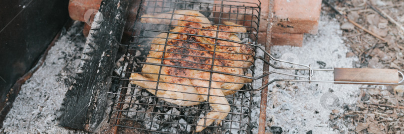 Скачать блюдо из куриного мяса, обжаренное на гриле на тлеющих углях или тлеющих угольках от костра на земле летним или осенним днем. барбекю в походных условиях. выживание в сельской местности и дикая деревенская жизнь фотосток Ozero