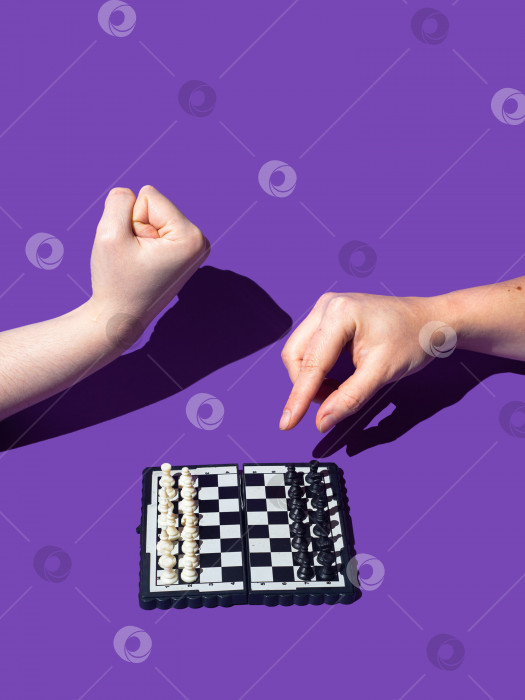 Скачать Двумя руками. Один игрок показывает кулак, другой игрок делает первый ход на шахматной доске. Не смей делать этот шаг! - как будто один игрок говорит другому, который пытается начать игру. фотосток Ozero