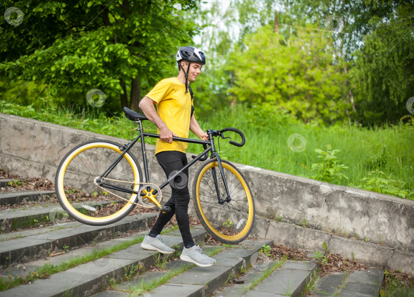 Скачать Молодой человек спускается по лестнице со своим велосипедом в общественном парке. фотосток Ozero