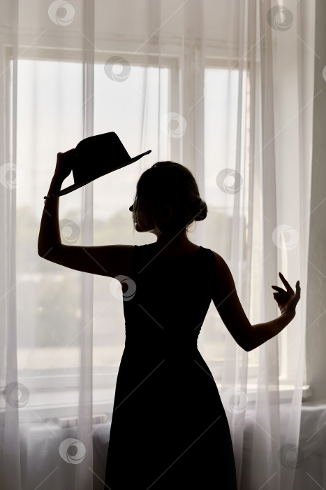 Скачать Черный силуэт женщины в платье и шляпе у окна фотосток Ozero