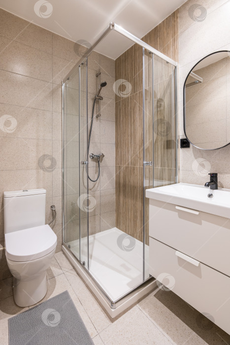 Скачать Дизайн современной ванной комнаты с модной мебелью, бежевой плиткой, современной раковиной и круглым зеркалом. фотосток Ozero