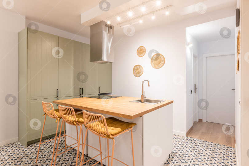 Скачать Светлая теплая кухня с бытовой техникой, деревянным островом и стульчиками для кормления в современной квартире фотосток Ozero