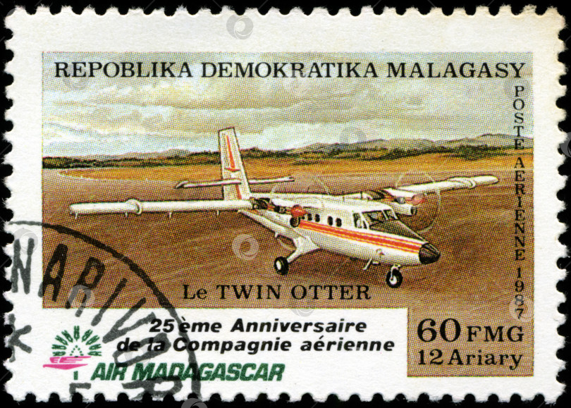 Скачать РЕСПУБЛИКА МАЛАГАСИЯ - ОКОЛО 1987 года: На марке, напечатанной на малагасийском языке (Мадагаскар), изображен самолет Twin Otter, около 1987 года фотосток Ozero