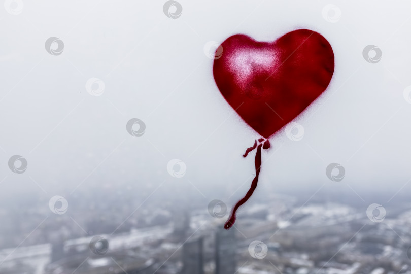Скачать Изображение маленькой девочки с воздушным шаром в форме сердца на стеклянном окне небоскреба в пасмурный зимний день. Городской пейзаж с высоты птичьего полета фотосток Ozero