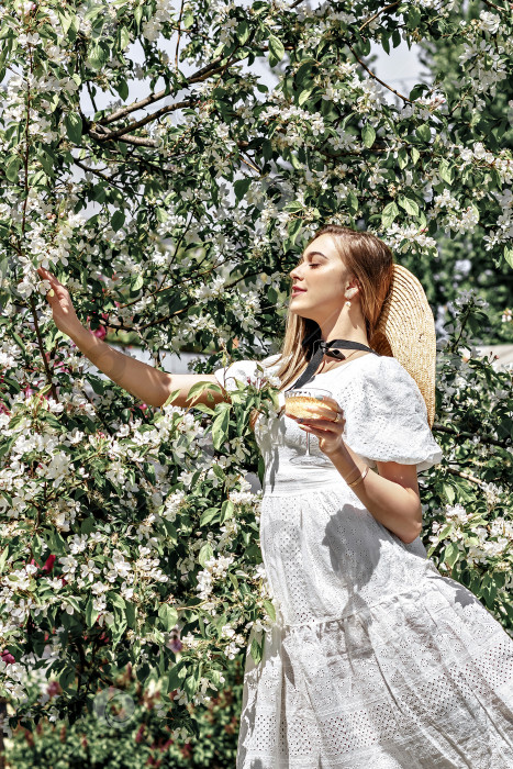 Скачать Белые цветы в саду. Молодая девушка стоит среди цветущих яблонь с бокалом вина в руке.Настроение счастья, туризм в Азии, цветущий традиционный сезонный фон апреля.Пикник фотосток Ozero