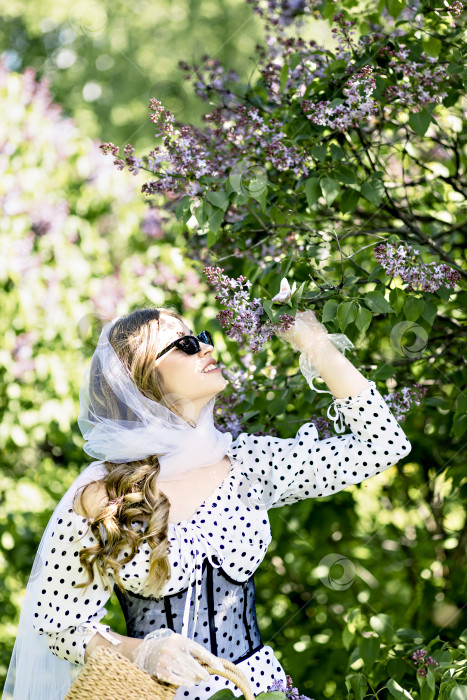 Скачать Портрет улыбающейся молодой девушки на фоне цветущих сиреневых деревьев. Летнее время, каникулы фотосток Ozero