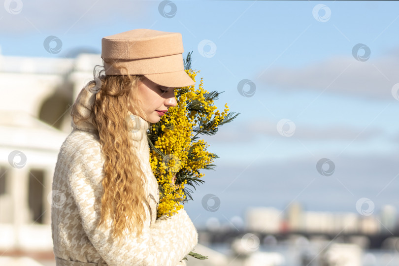 Скачать Молодая женщина стоит с букетом желтой мимозы и нюхает цветы. Концепция весеннего праздника - 8 марта, Пасха, Женский день фотосток Ozero