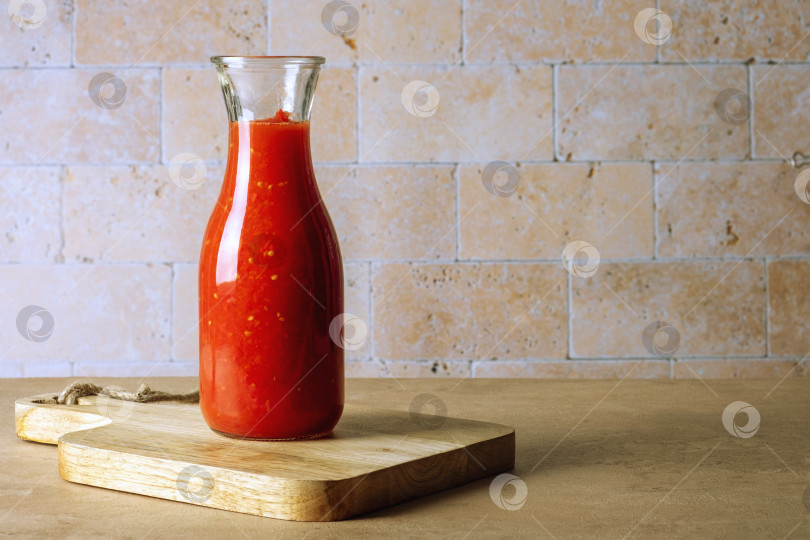Скачать Стеклянная банка бутылка с домашним томатным соусом стоит на деревянной разделочной доске фотосток Ozero