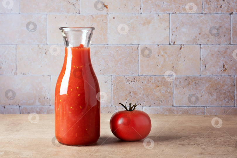 Скачать Стеклянная бутылка с домашним томатным соусом и спелыми помидорами на столе. фотосток Ozero