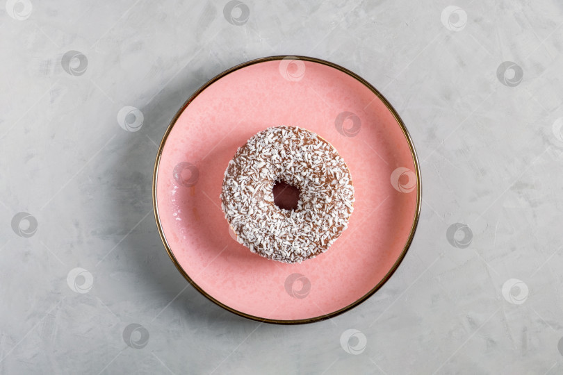 Скачать Пончик с кокосовой посыпкой лежит на розовой керамической тарелке фотосток Ozero