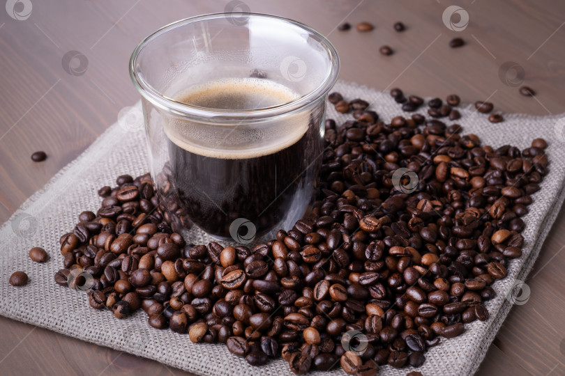 Скачать Стеклянная чашка с кофе и горкой обжаренных кофейных зерен фотосток Ozero