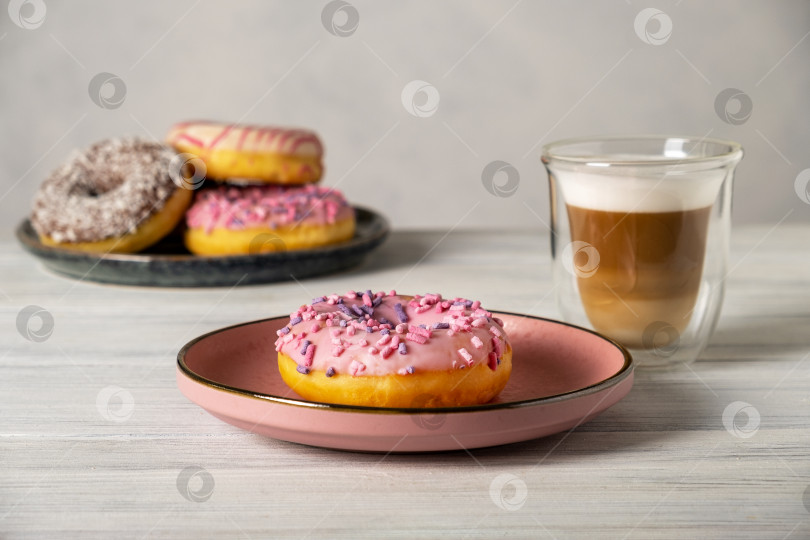 Скачать Глазированные пончики на тарелках и кофе с молочной пенкой в термостойкой чашке. фотосток Ozero