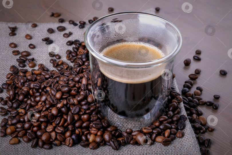 Скачать Стеклянная чашка с кофе и горкой обжаренных кофейных зерен фотосток Ozero