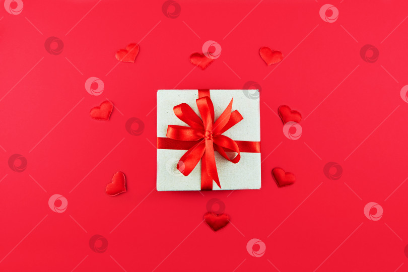 Скачать Подарочная коробка в упаковке из крафт-бумаги с красной лентой на красном фоне. День Святого Валентина, День матери, День рождения. фотосток Ozero