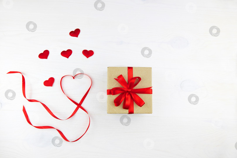 Скачать Подарочная коробка в упаковке из крафт-бумаги с красной лентой и лентой в форме сердца на белом фоне. день святого Валентина. фотосток Ozero
