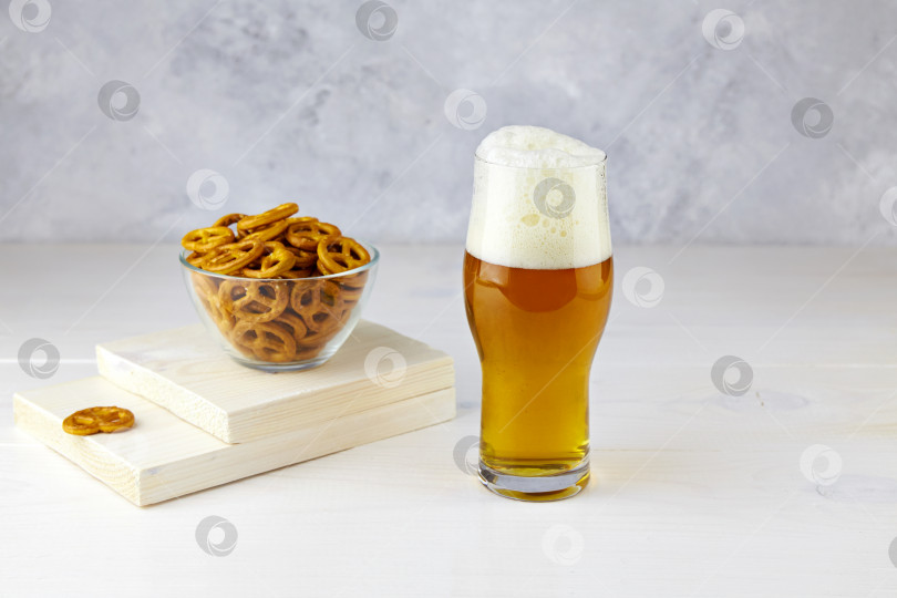 Скачать Бокал светлого пива с крендельками на белом деревянном фоне фотосток Ozero