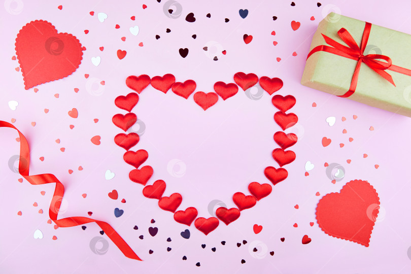 Скачать Фон на День Святого Валентина. Подарок, красные ленты, декоративные сердечки, конфетти на розовом фоне фотосток Ozero