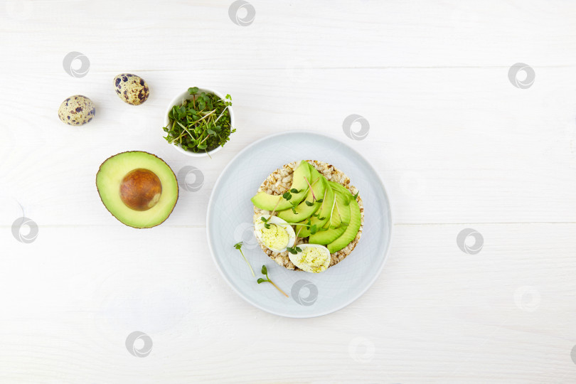 Скачать Цельнозерновой тост с яйцом, авокадо и микрозеленью на белом деревянном фоне. фотосток Ozero