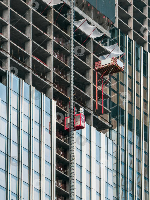 Скачать Лифты поднимают на строительные площадки строящегося небоскреба. фотосток Ozero