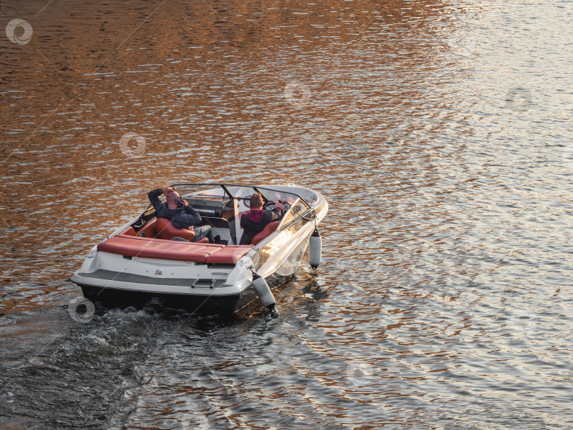 Скачать Роскошная моторная лодка стоит на воде на закате. Отдохните на моторной лодке. фотосток Ozero