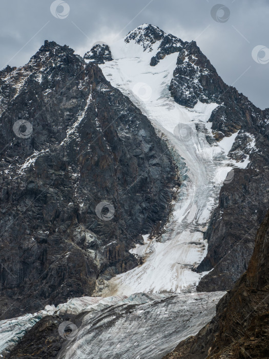 Скачать Вертикальный вид на Большой ледник высоко в горах, покрытый снегом и льдом. Зимний пейзаж Алтая. фотосток Ozero