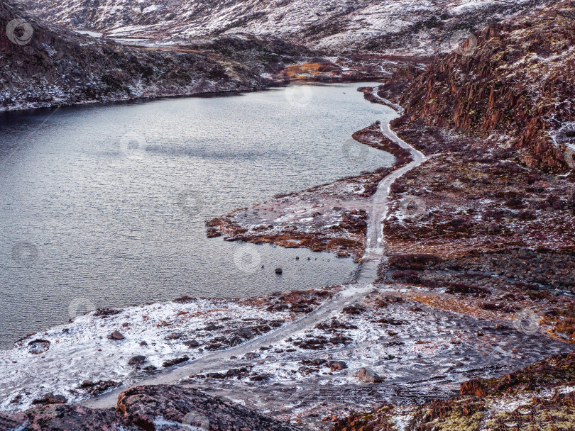 Скачать Обледенелая зимняя дорога через тундровые холмы в Териберке. Удивительный красочный арктический пейзаж фотосток Ozero