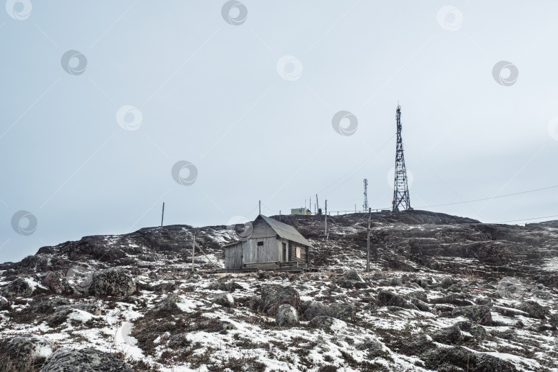 Скачать Вышки сотовой связи на заснеженных холмах в тундре. Старый дом на заснеженном полярном холме фотосток Ozero