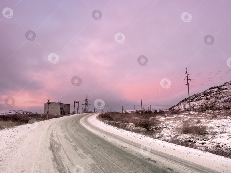 Скачать Снежный поворот на дороге, уходящей вдаль между холмами. Волшебный пурпурный цвет рассвета. фотосток Ozero