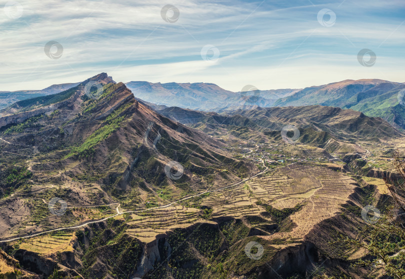 Скачать Горная долина. Скалистые уступы, уходящие вдаль на фоне гор, покрытых редкой растительностью. фотосток Ozero