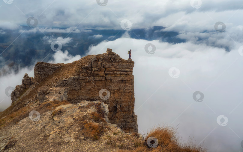 Скачать Турист прогуливается по горе у края пропасти на большой высоте под фотосток Ozero