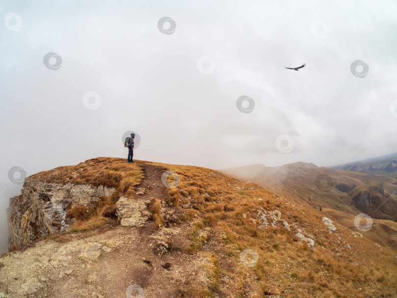Скачать Турист прогуливается по горе у края пропасти на большой высоте под фотосток Ozero