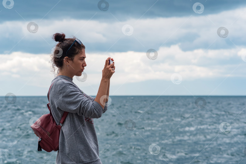 Скачать женщина, снимающая море на смартфон фотосток Ozero