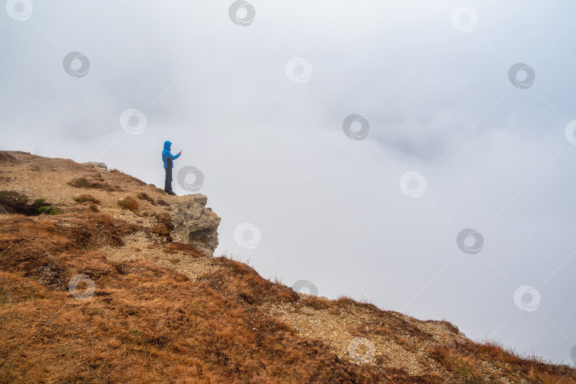 Скачать Турист фотографирует на горе у края пропасти на большой высоте фотосток Ozero