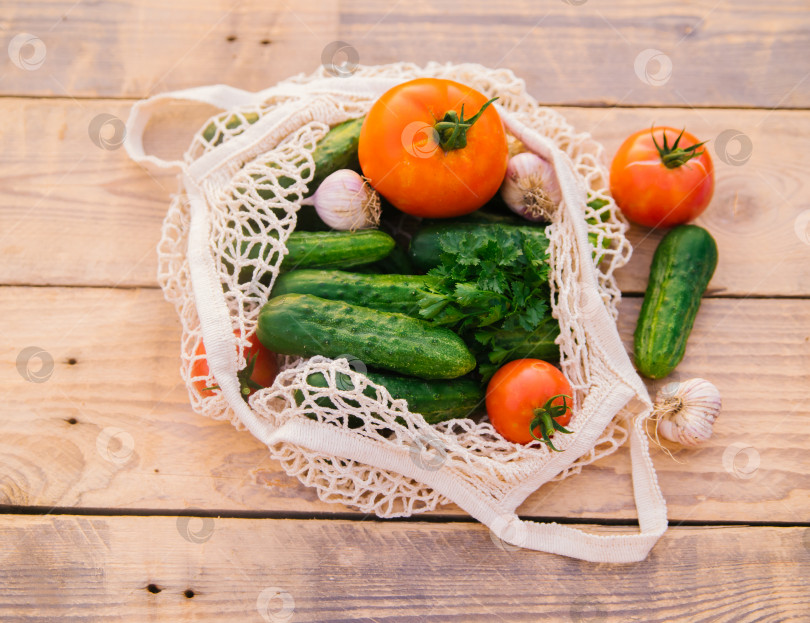 Скачать Свежие сочные овощи, продукты в многоразовой хозяйственной сумке, авоське из переработанных материалов, на деревянном столе в саду. Вегетарианство. Никакого пластика. Экологически чистый образ жизни. фотосток Ozero