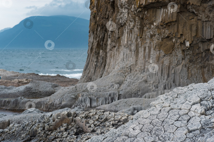 Скачать облачный скалистый берег моря, образованный столбчатым базальтом на фоне штормового моря, прибрежный пейзаж Курильских островов фотосток Ozero