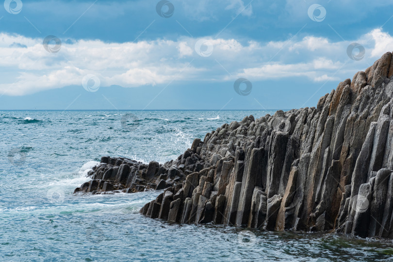 Скачать скалистый берег моря, образованный столбчатым базальтом на фоне прибоя, прибрежный пейзаж острова Кунашир фотосток Ozero