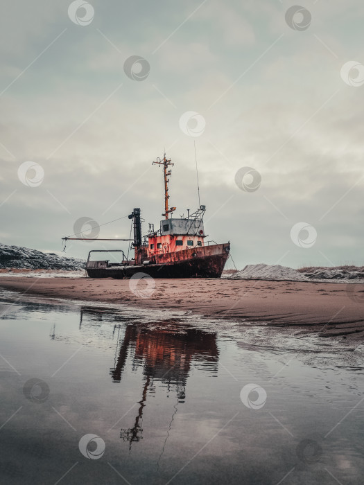 Скачать Старую ржавую рыбацкую лодку выбросило на песчаный пляж в Баренцевом море. Подлинное Северное море. Териберка. фотосток Ozero