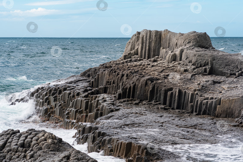 Скачать скалистый берег моря, образованный столбчатым базальтом на фоне штормового моря, прибрежный ландшафт Курильских островов фотосток Ozero