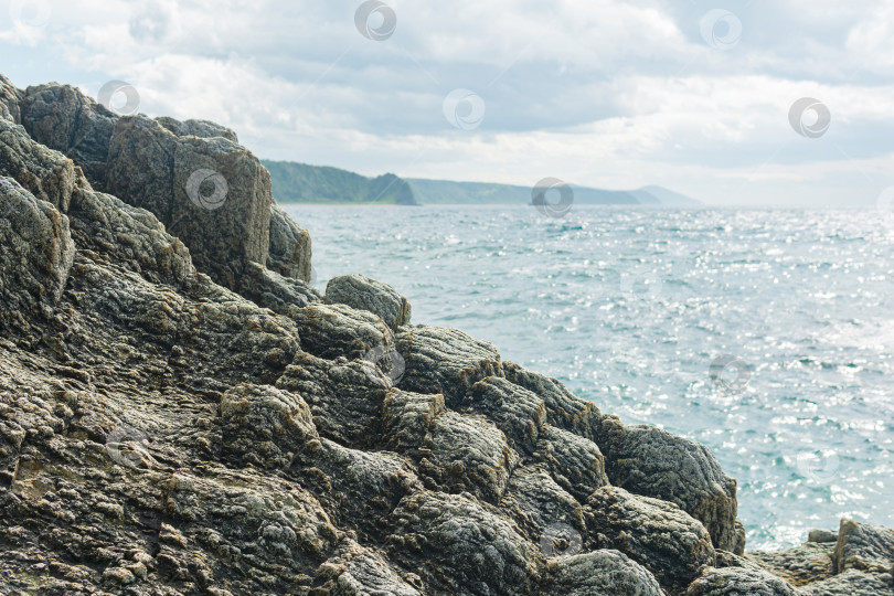 Скачать прибрежный утес, образованный застывшей лавой крупным планом на фоне далекого морского берега фотосток Ozero