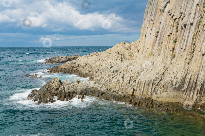 Скачать скалистый берег моря, образованный столбчатым базальтом на фоне моря, прибрежный пейзаж Курильских островов фотосток Ozero
