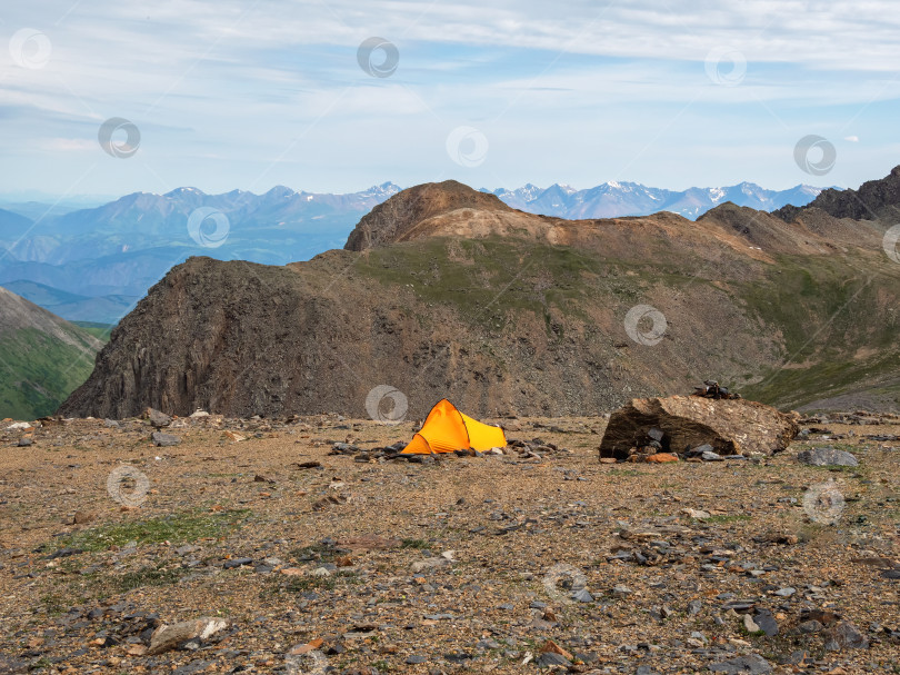Скачать Летний кемпинг в горах. Яркий альпийский пейзаж с ярко-оранжевым шатром на очень большой высоте с видом на высокую гору и большой ледник в драматических облаках. Потрясающий горный пейзаж с палаткой. фотосток Ozero