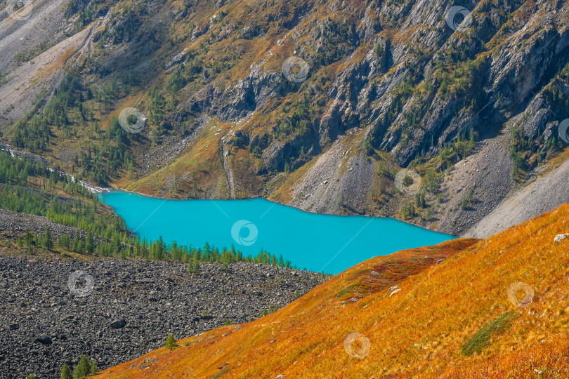 Скачать Бирюзовое озеро в кальдере. Глубокое горное озеро голубого цвета среди высоких гор в солнечную погоду. Чудесный яркий вид на темно-синее горное озеро среди залитых осенним солнцем скал. фотосток Ozero