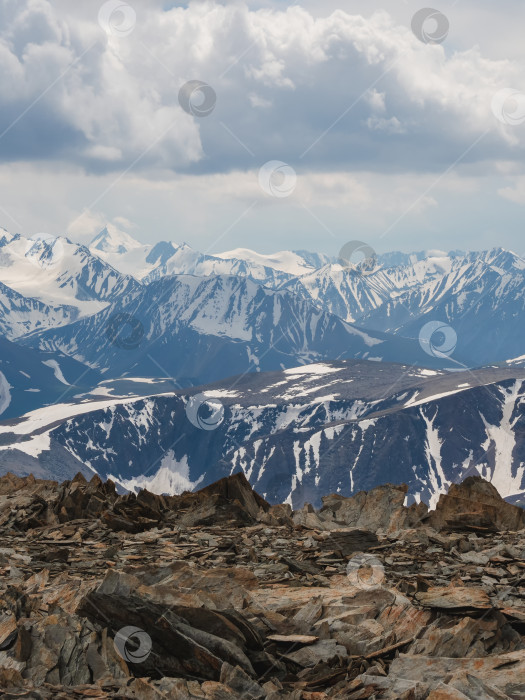 Скачать Впечатляющий вид с высоты птичьего полета на большой снежный горный хребет под переменчивым дождливым облачным небом. Яркий атмосферный альпийский пейзаж с высокой заснеженной горной вершиной в низких облаках. фотосток Ozero
