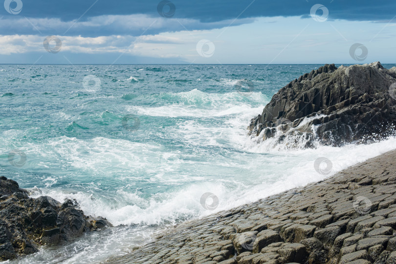 Скачать скалистый берег моря, образованный столбчатым базальтом на фоне прибоя, прибрежный ландшафт Курильских островов фотосток Ozero
